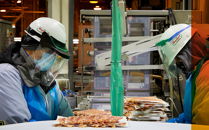 Hormel factory employees looking down at bacon conveyor belt